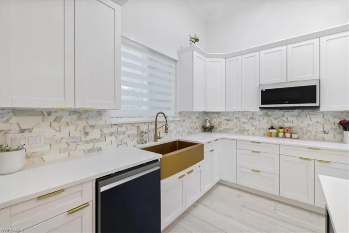 Kitchen with white cabinetry, dishwasher, white microwave, tasteful backsplash, and light wood finished floors