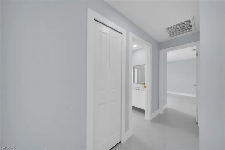 Hallway with light gray walls, white trim, and light gray tiled flooring