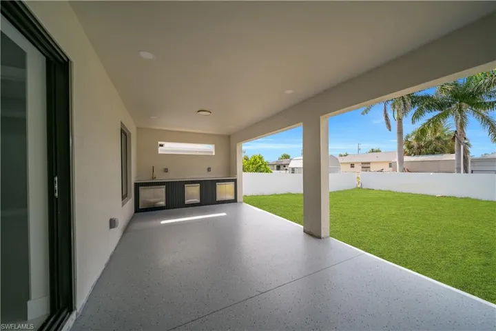 Covered patio featuring an outdoor kitchen with built-in cabinetry, stainless steel appliances, and a sink
