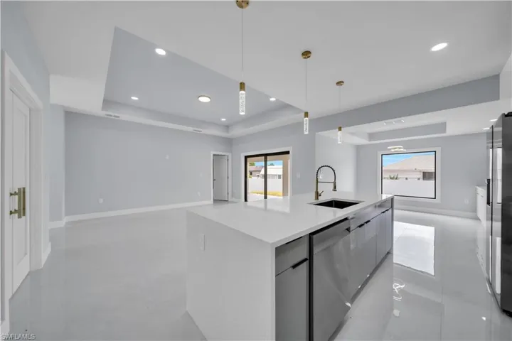 Modern kitchen island featuring a waterfall countertop, integrated sink with a gooseneck faucet, and stainless steel appliances