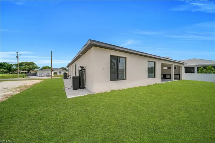 Exterior featuring a neutral stucco finish, dark framed windows, and a dark shingle roof