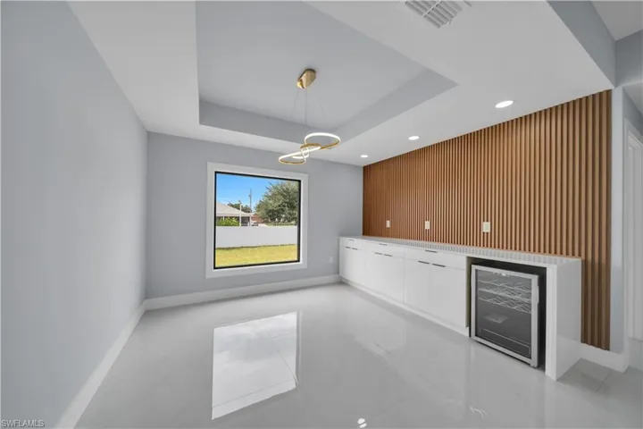 Recessed ceiling with a contemporary chandelier above glossy tile flooring