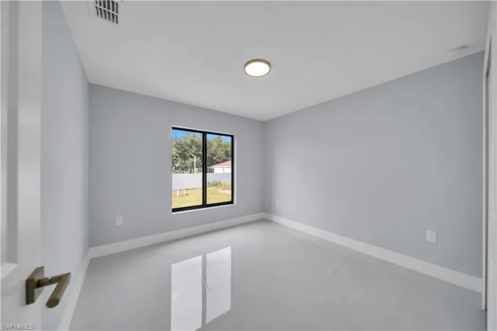 Bright interior space featuring light gray walls, white trim, and glossy tile flooring
