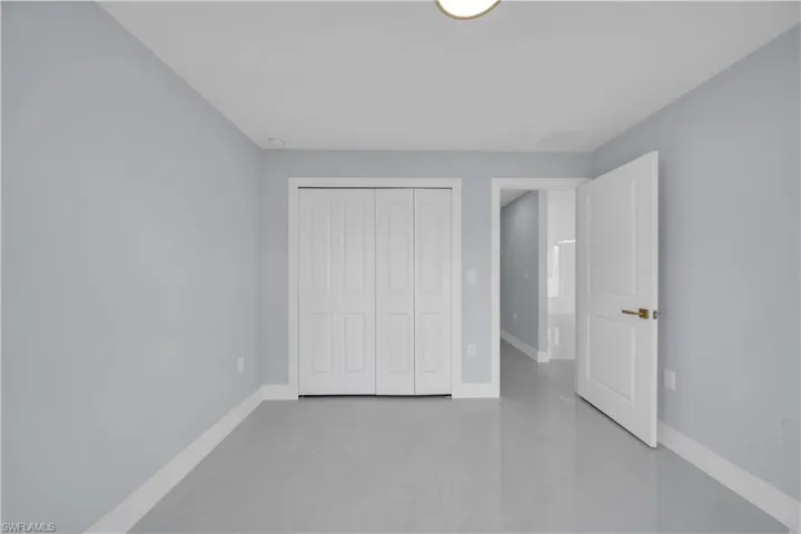 Spacious interior room featuring light gray walls, white baseboards, and neutral tile flooring
