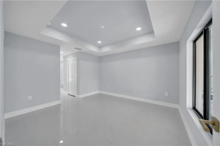 Spacious interior room featuring light-toned walls and polished tile flooring