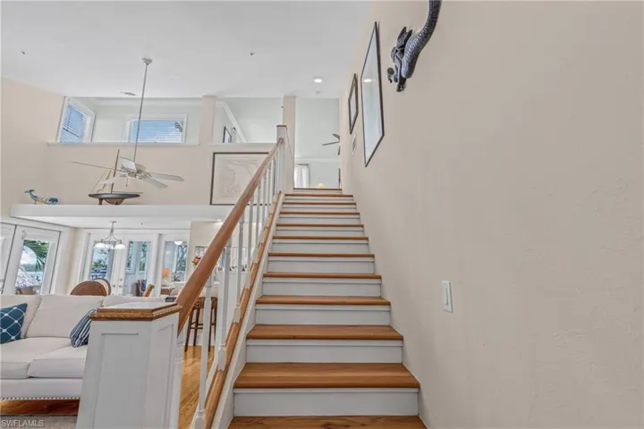 Stairs with wood finished floors, a high ceiling, and ceiling fan