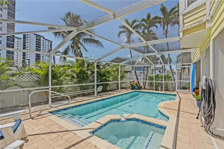 View of swimming pool featuring a pool with connected hot tub, a patio area, a sunroom, and glass enclosure