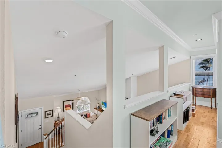Corridor with an upstairs landing, crown molding, light wood-type flooring, and recessed lighting
