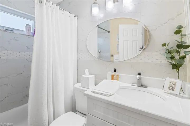 Bathroom with vanity, tile walls, and shower / tub combo with curtain