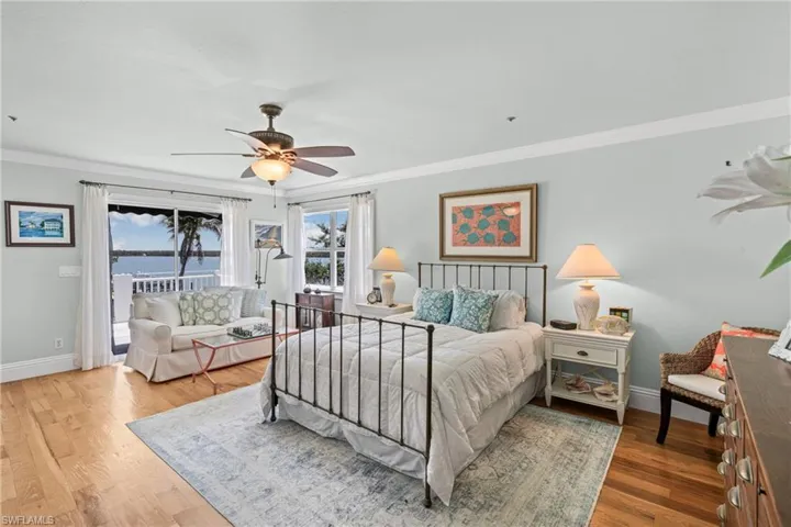Bedroom featuring crown molding, a water view, access to outside, wood finished floors, and a ceiling fan