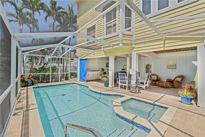 View of swimming pool featuring a patio, a lanai, a pool with connected hot tub, and a sunroom