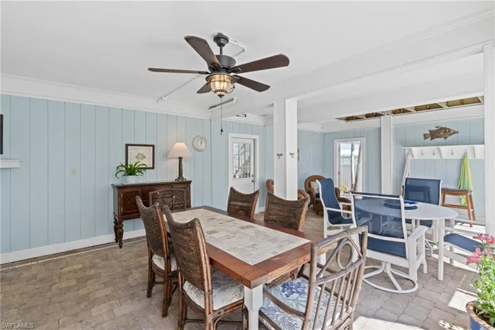 Dining area with ceiling fan, crown molding, and wood walls