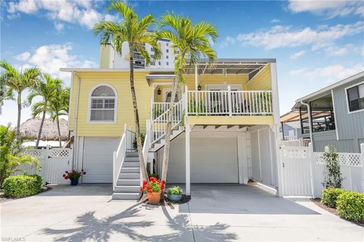 Raised beach house with a gate and driveway