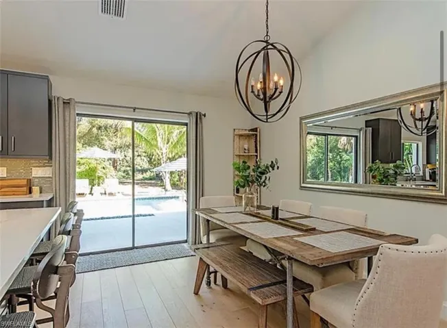 Dining room with light wood-style flooring, suspended lighting, and healthy amount of natural light