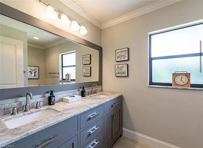 Bathroom featuring double vanity, crown molding, and light wood finished floors