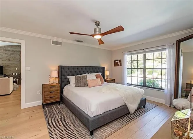 Bedroom featuring light wood-type flooring, crown molding, and a ceiling fan