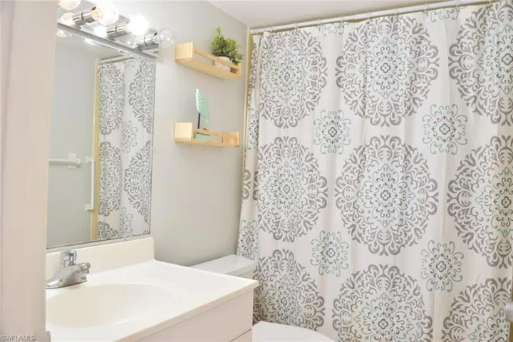 Bathroom featuring a single vanity with an integrated sink, polished chrome faucet, and a large wall-mounted mirror