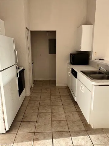 Kitchen featuring white cabinetry, white appliances, light countertops, and light tile patterned floors