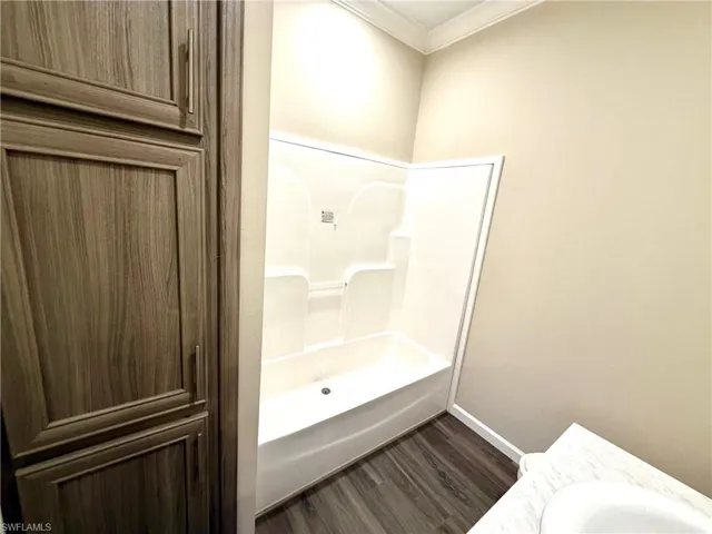 Bathroom featuring ornamental molding, dark wood-style flooring, vanity, and shower / tub combination