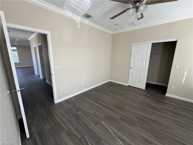Unfurnished bedroom with crown molding, dark wood finished floors, a closet, ceiling fan, and recessed lighting