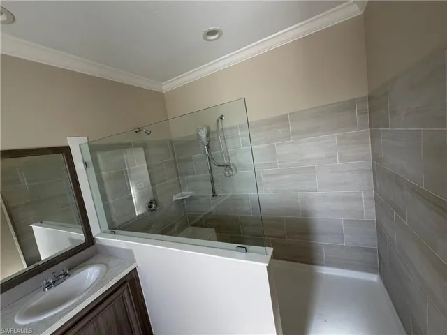 Full bath with a walk in shower, vanity, and ornamental molding