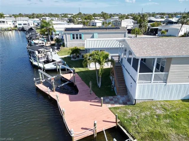 Dock area featuring boat lift, a lawn, a residential view, and a water view