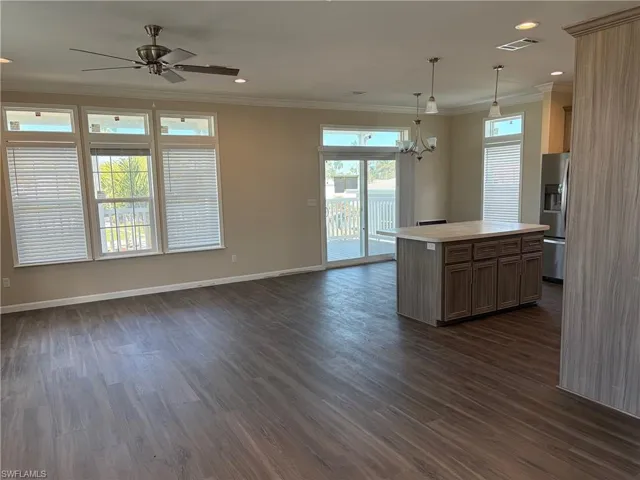 Kitchen with light countertops, a center island, open floor plan, stainless steel fridge, and crown molding