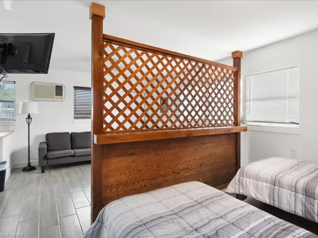 Bedroom with wood finish floors and a wall mounted AC