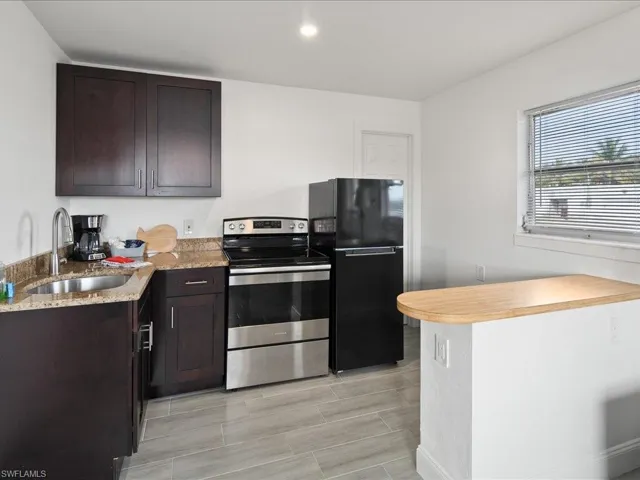 Kitchen with stainless steel range with electric cooktop, freestanding refrigerator, dark wood finish cabinets, and a peninsula