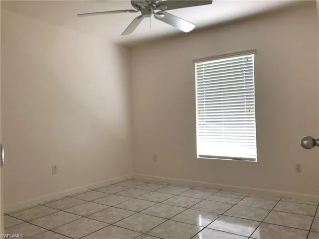 Empty room with light tile patterned flooring and ceiling fan