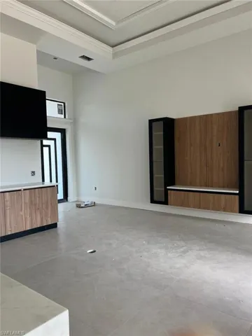 Unfurnished living room featuring ornamental molding, a towering ceiling, concrete flooring, and a tray ceiling