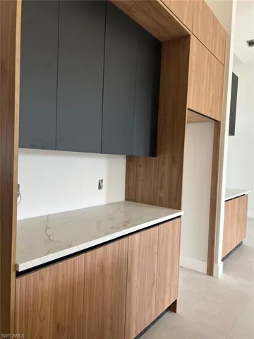 Kitchen featuring modern cabinets, light stone counters, and brown cabinets