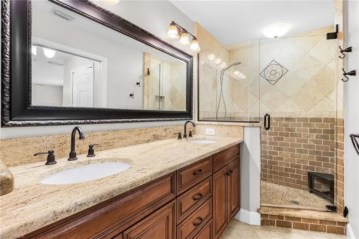 Bathroom with a shower stall, double vanity, and light tile patterned flooring