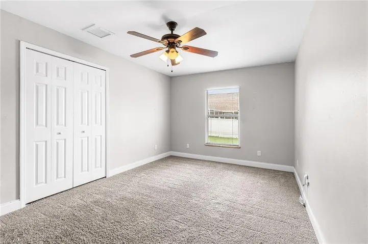 Unfurnished bedroom with light colored carpet, a ceiling fan, and a closet