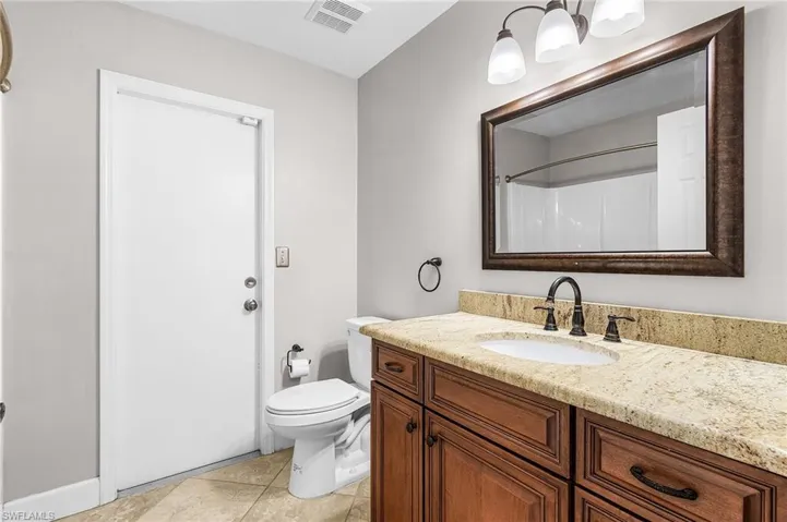 Bathroom with vanity, light tile patterned floors, and a shower
