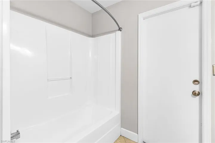 Full bathroom with shower / washtub combination and light tile patterned floors