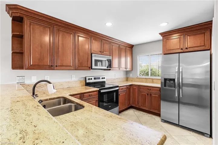Kitchen featuring stainless steel appliances, open shelves, light stone counters, light tile patterned flooring, and recessed lighting