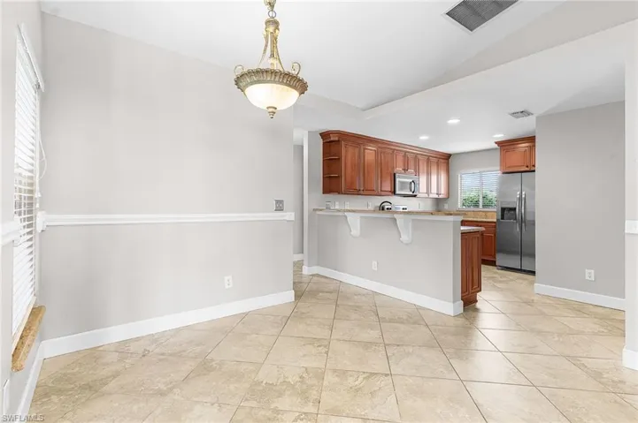 Kitchen featuring a breakfast bar area, brown cabinetry, a peninsula, appliances with stainless steel finishes, and open shelves