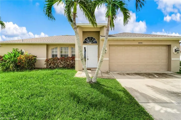 Single story home with stucco siding, concrete driveway, a garage, and a front lawn