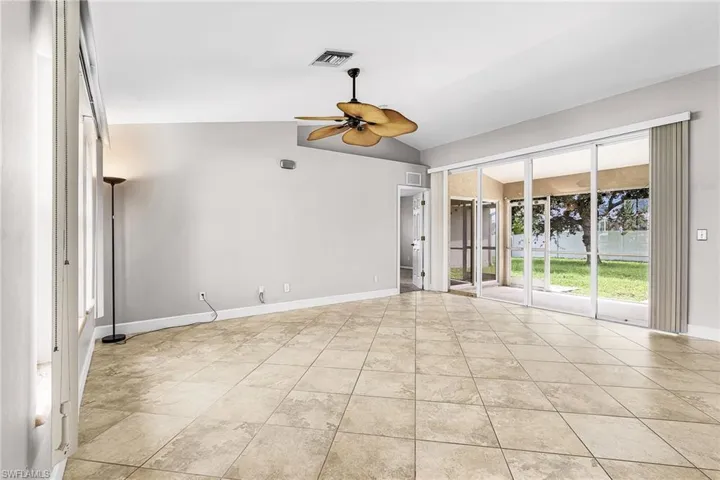 Spare room featuring vaulted ceiling, ceiling fan, and light tile patterned flooring