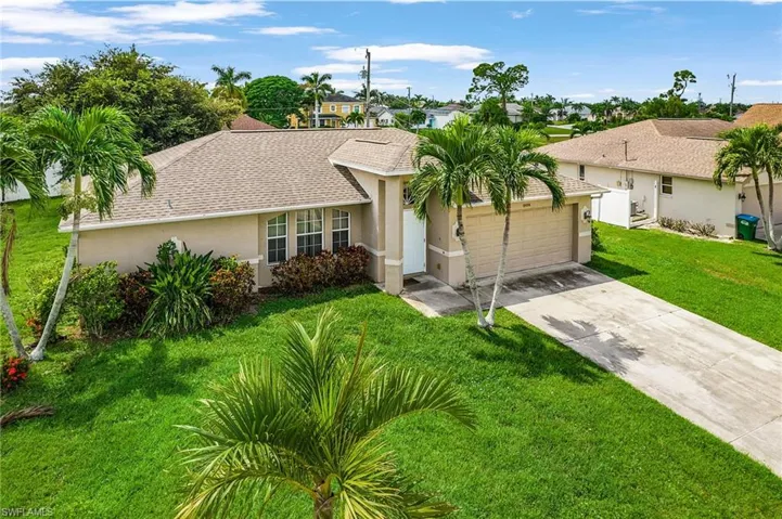 Ranch-style home featuring stucco siding, driveway, a front lawn, a shingled roof, and an attached garage