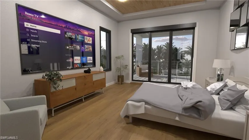 Bedroom featuring a tray ceiling, access to exterior, and wood finished floors