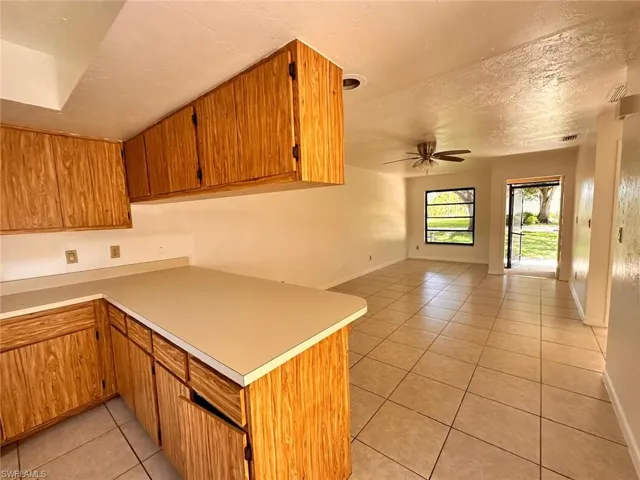 Kitchen featuring ceiling fan, a textured ceiling, kitchen peninsula, and light tile patterned floors