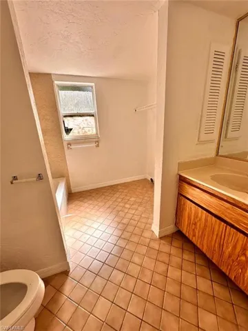 Bathroom with tile patterned floors, vanity, toilet, and a textured ceiling