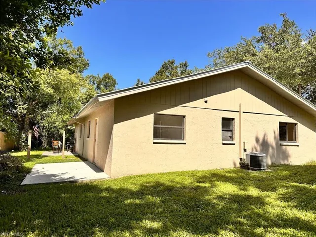 Rear view of house with central AC, a yard, and a patio area