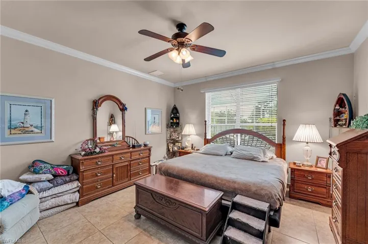 Tiled bedroom with crown molding and ceiling fan