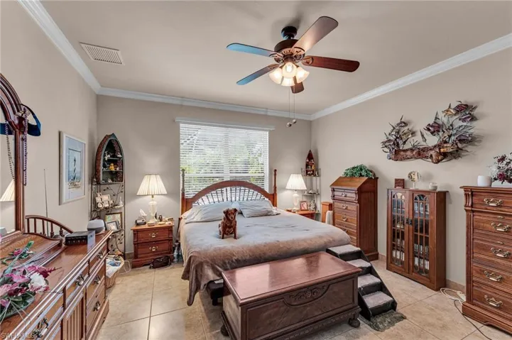 Bedroom with crown molding, ceiling fan, and light tile patterned flooring