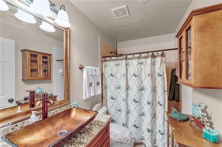 Bathroom featuring a shower with curtain, toilet, a textured ceiling, and vanity