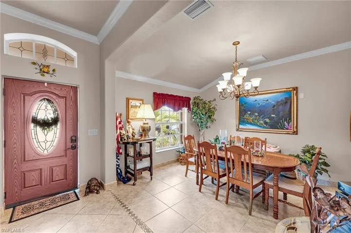 Dining area with ornamental molding, a chandelier, and light tile patterned flooring