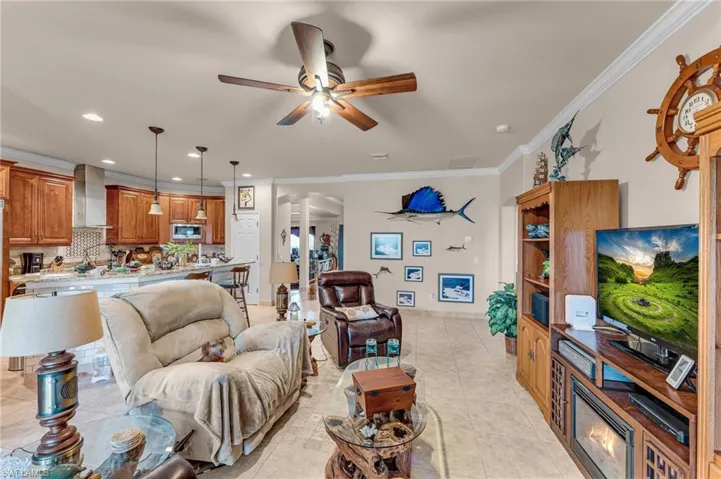Tiled living room with ceiling fan and ornamental molding